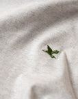 Close-up of a white t-shirt with a green embroidered Heron logo. Design by The Handmade cyclist.