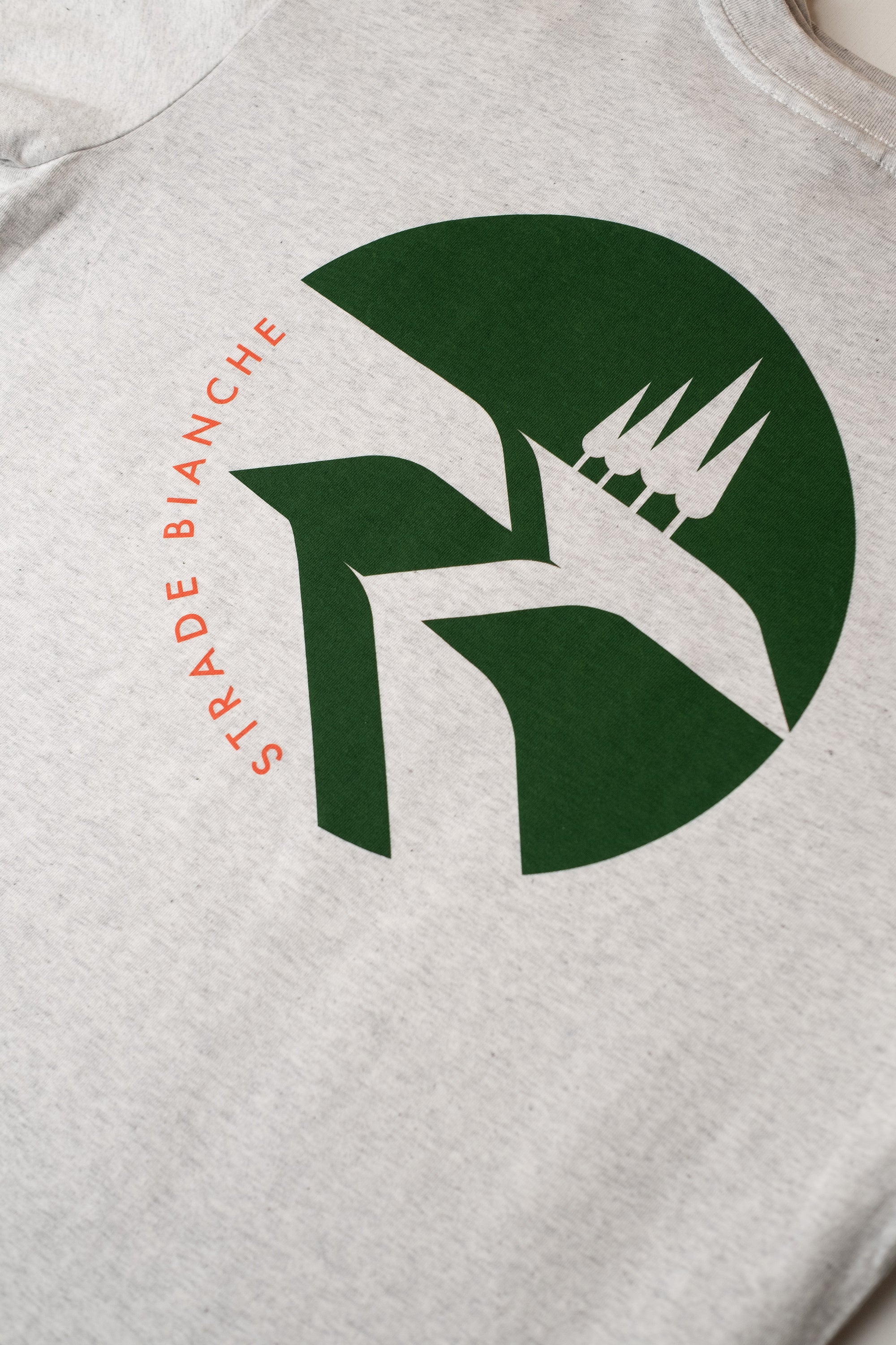 Close-up of a white t-shirt with a green print featuring Strade Bianchi design by The Handmade cyclist.