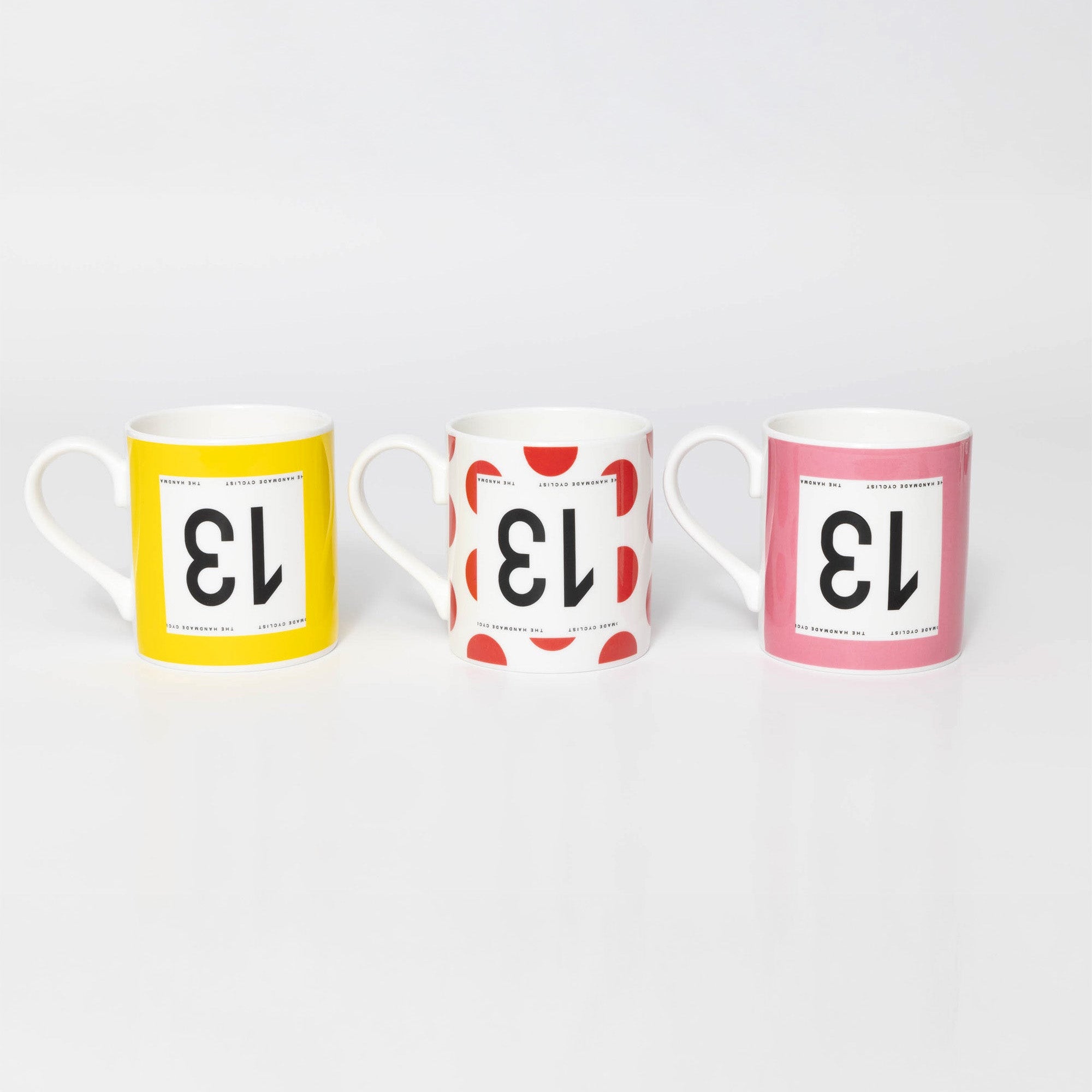 Three mugs with different designs of cycling jerseys from the Tour De France and Giro D'Italia on a white background