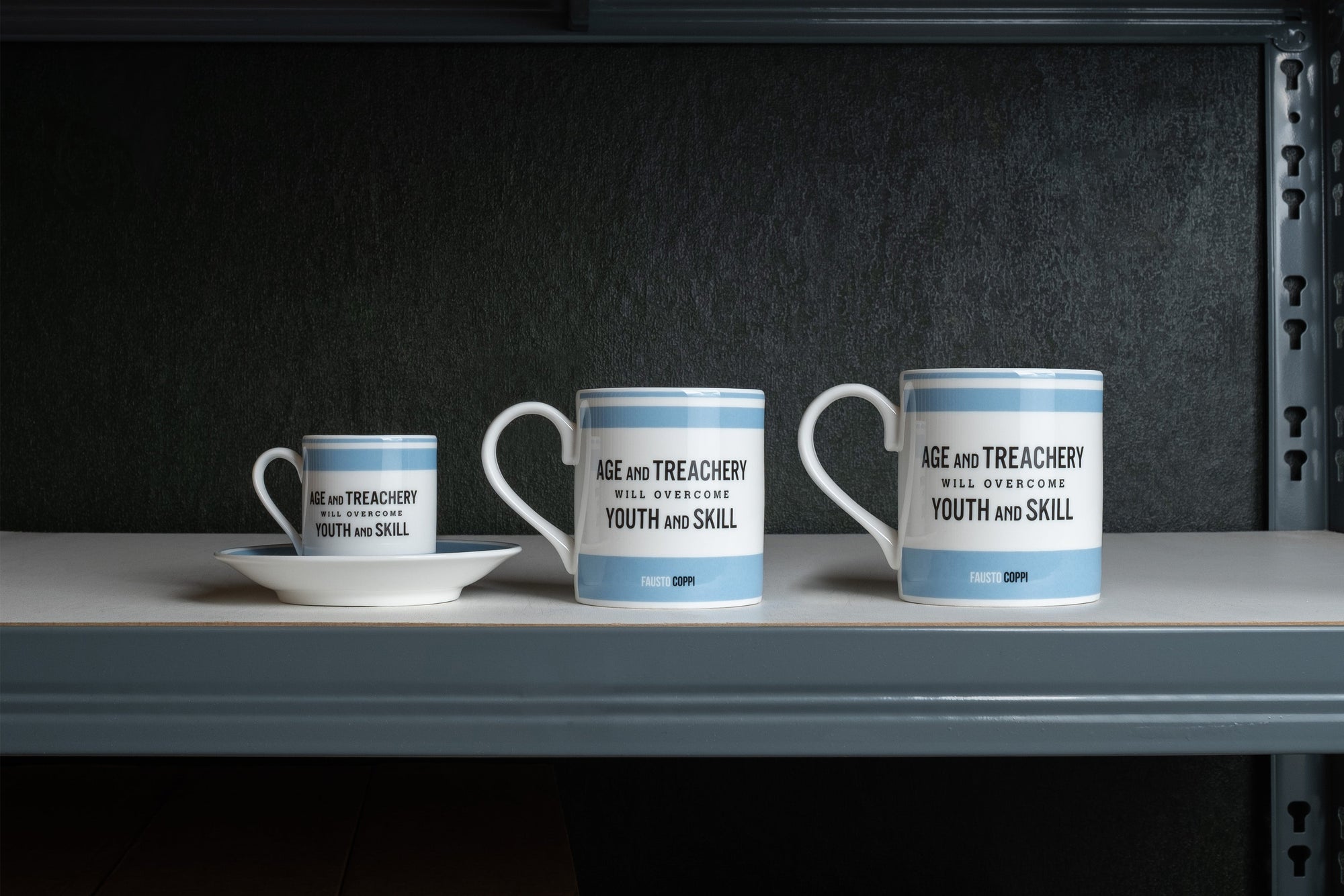 Three mugs with quote from legendary cyclist Fausto Coppi, on a shelf against a dark background
