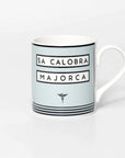 Mug with cyclist destination Sa Calobra. Design features mountain and sun on a white background