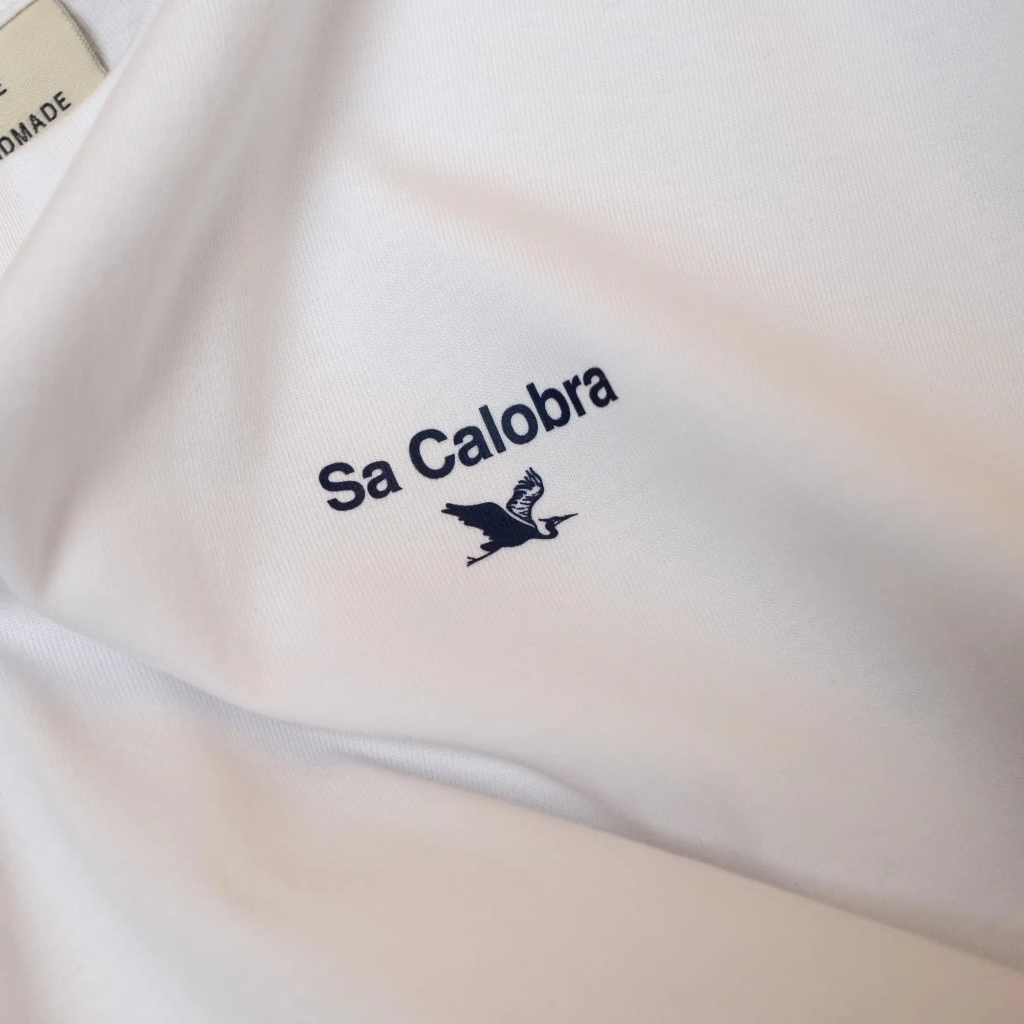 Close-up of white Climbs Profiles T-shirt with cycling climb 'Sa Calobra' logo, by the Handmade Cyclist